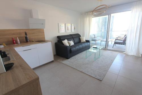 a living room with a black couch and a table at Sun Paradise SeaView&Terrace Parking&Pool in Beausoleil