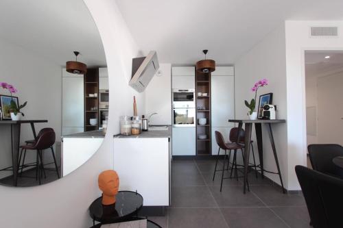 a kitchen with white cabinets and bar stools at Sun Paradise SeaView&Terrace Parking&Pool in Beausoleil