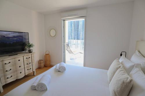 a white bedroom with a large bed and a television at Sun Paradise SeaView&Terrace Parking&Pool in Beausoleil
