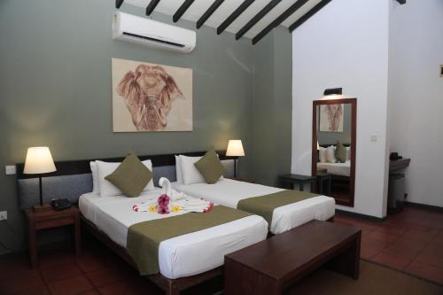 a hotel room with two beds and a mirror at Hotel Elephant Reach in Yala