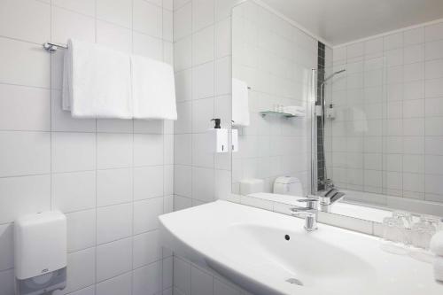 a white bathroom with a sink and a mirror at Scandic Vestfjord Lofoten in Svolvær