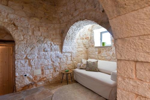 a living room with a white couch in a stone wall at Borgo Elaia in Cisternino