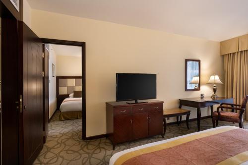 a hotel room with a television and a bedroom at Grand Hotel Excelsior in Valletta