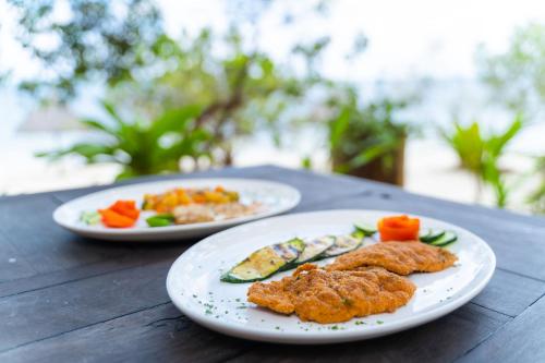 two plates of food on a wooden table at Pole Pole Bungalows in Utende