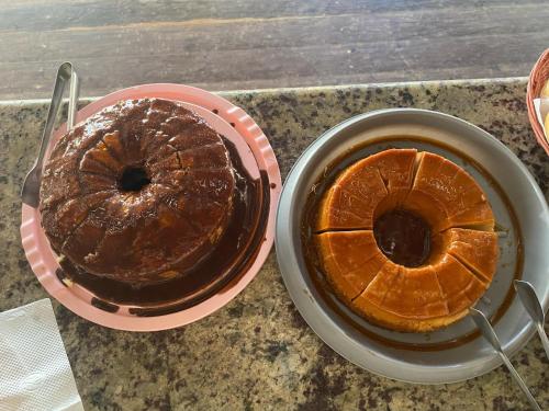 two cakes on a table with a plate and a cup of coffee at iapôi Beira-Mar Maracaípe in Porto De Galinhas