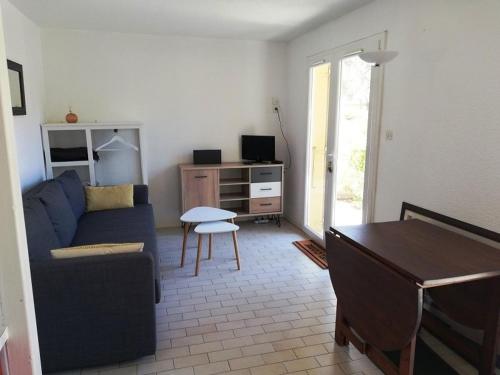 un salon avec un canapé bleu et une table dans l'établissement AGREABLE APPARTEMENT AVEC PARKING DANS UNE RESIDENCE ARBOREE TRES CALME, au Cap d'Agde