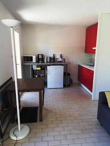 une cuisine avec des armoires rouges et un réfrigérateur blanc dans l'établissement AGREABLE APPARTEMENT AVEC PARKING DANS UNE RESIDENCE ARBOREE TRES CALME, au Cap d'Agde