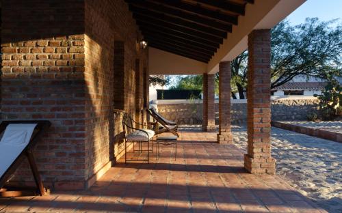 a porch with two chairs and a brick wall at La Vaca Tranquila in San Carlos