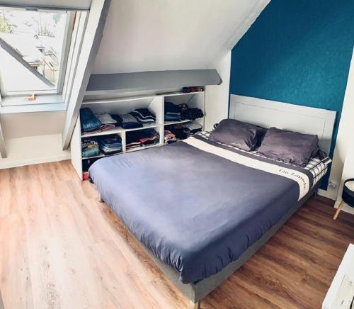 une chambre avec un lit avec un mur bleu dans l'établissement Charmant appartement T3 avec terrasse en rez de jardin sur le Golf e L'Odet, à Bénodet