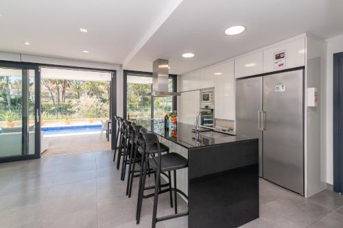 a kitchen with a counter with chairs and a refrigerator at Beach Villa Cosins 1 Mel by Sealand Villas in Alcudia