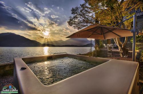 a bath tub with an umbrella next to a body of water at Villa Scoglio in Varenna