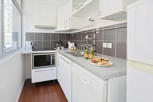 une cuisine blanche avec une plaque de cuisson sur un comptoir dans l'établissement Le Modulor Cité du Design, à Saint-Étienne