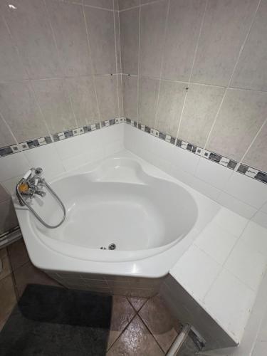 a white bath tub in a tiled bathroom at Cosy room 1 s in Streatham Vale