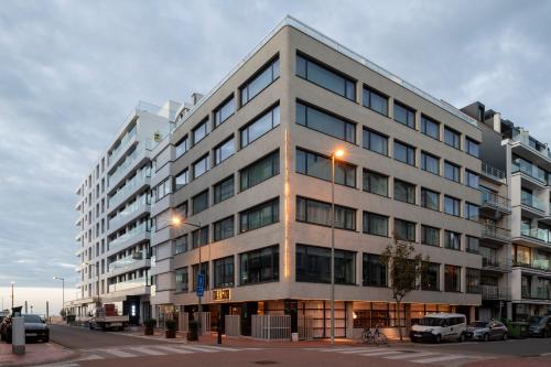 a large building on a street with cars parked in front at Hotel Nelson in Knokke-Heist