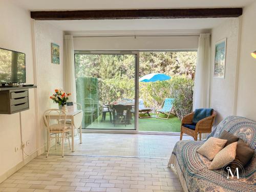 un salon avec un canapé et une porte coulissante en verre dans l'établissement Studio rez de jardin dans résidence avec piscine, à Bandol