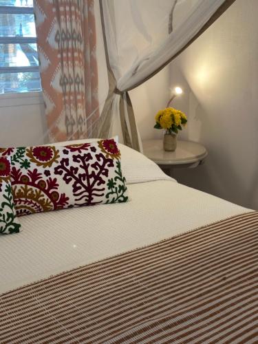 a bedroom with a bed with two pillows and a window at MADIROKELY HOUSE Nosy Be in Ambatoloaka