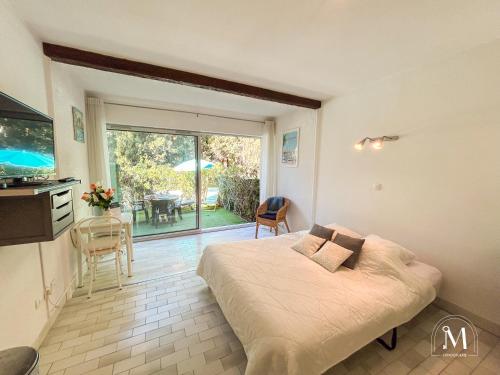 une chambre avec un lit et une cuisine avec une table dans l'établissement Studio rez de jardin dans résidence avec piscine, à Bandol