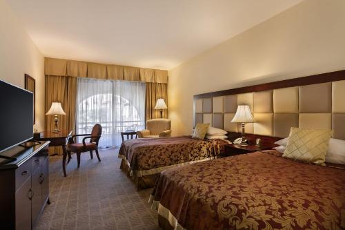 a hotel room with two beds and a television at Grand Hotel Excelsior in Valletta
