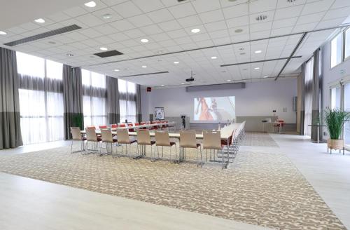 a conference room with a table and chairs and a presentation at Mercure Grenoble Centre Porte des Alpes in Grenoble