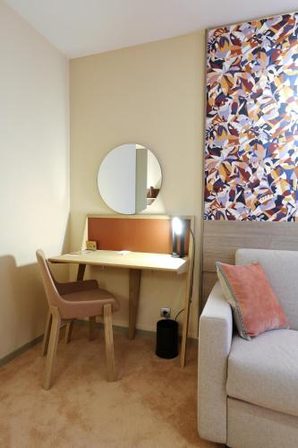 a room with a desk with a mirror and a couch at Mercure Grenoble Centre Porte des Alpes in Grenoble