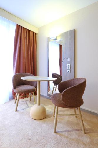 a room with a table and two chairs and a lamp at Mercure Grenoble Centre Porte des Alpes in Grenoble