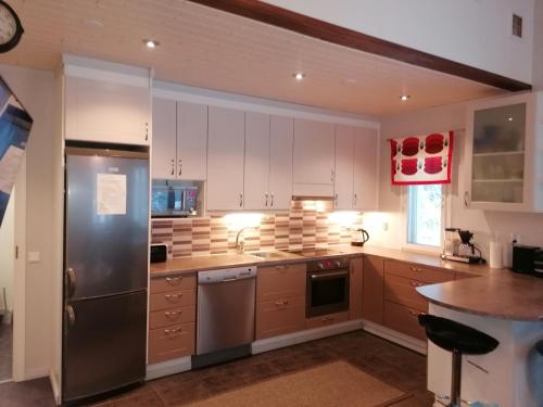 a kitchen with white cabinets and a stainless steel refrigerator at Majoituspalvelu Nurmi Oy Välitie 3B Saunallinen in Raahe