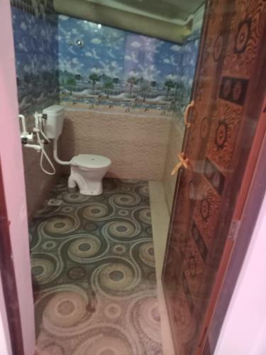 a bathroom with a toilet and a painting on the wall at AJJA AND SONS in Gokarna
