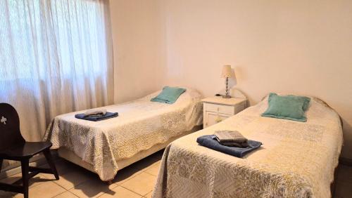 Un dormitorio con dos camas y una silla y una ventana. en SOHO Chacras de Coria Casa Completa, en Chacras de Coria