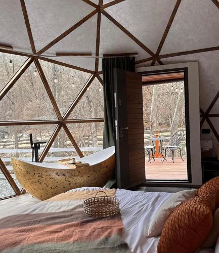 a bedroom with a tub in a room with a window at Riverside Dome in Dobra
