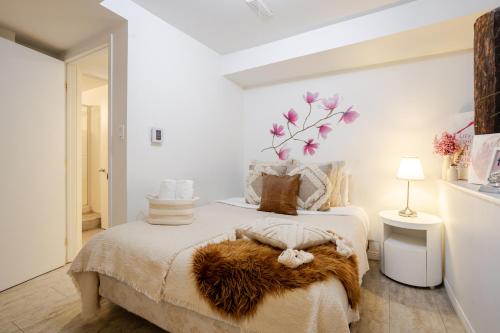 a white bedroom with a bed with a brown blanket at Majestic Villa in Downtown Griffintown in Montréal