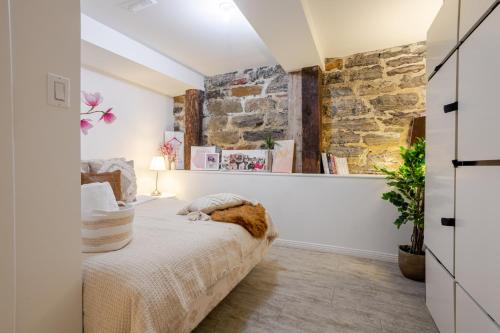 a bedroom with a bed and a stone wall at Majestic Villa in Downtown Griffintown in Montréal