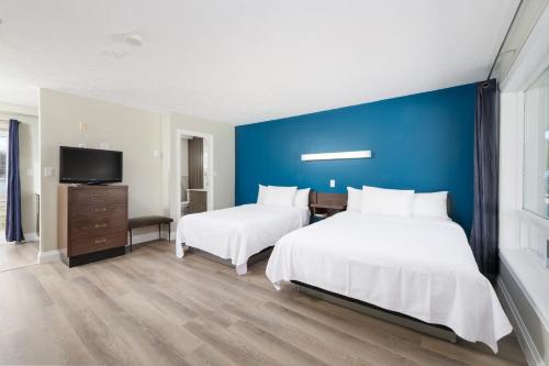 une chambre avec deux lits et un mur bleu dans l'établissement Lions Head Beach Motel & Cottages - WATERFRONT, à Lion's Head