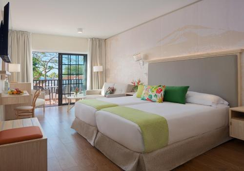 a large bedroom with a large bed and a living room at Hotel Jardín Tecina in Playa de Santiago