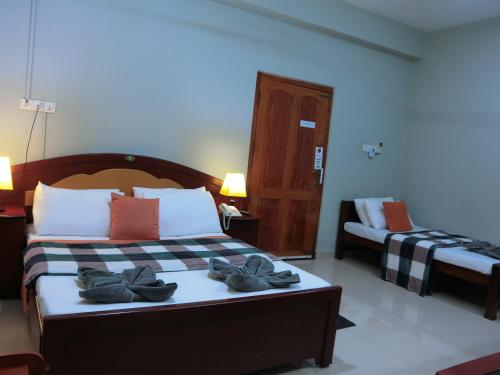 a bedroom with a bed with towels on it at SATK INN Jaffna, Kokkuvil in Kokkuvil East