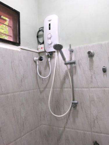 a shower in a bathroom with a hair dryer at SATK INN Jaffna, Kokkuvil in Kokkuvil East