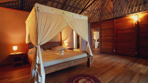a bedroom with a bed with a canopy at Manja Kely Lodge in Nosy Be