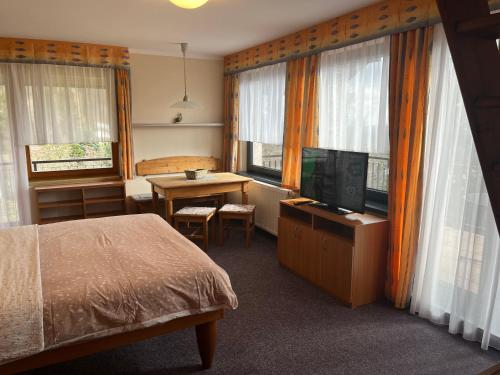 a bedroom with a bed and a desk with a television at apartmány Šnek - ať si děti hrají in Benecko