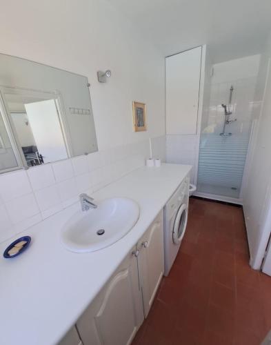 La salle de bains blanche est pourvue d'un lavabo et d'un lave-linge. dans l'établissement TROPCOQ - Au coeur de St-Tropez - Studio cabine pour 2 personnes, à Saint-Tropez