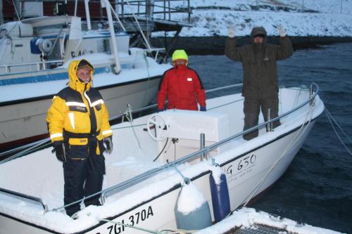 three people standing on a boat in the snow at Hotel Repvåg in Repvåg