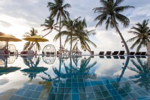 a swimming pool with palm trees and the ocean at Tango Luxe Beach Villa, Koh Samui - SHA Extra Plus in Choeng Mon Beach