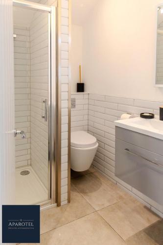 a bathroom with a shower and a toilet and a sink at Aparotel Serviced Apartments - Stonehenge, Amesbury Town Centre in Amesbury