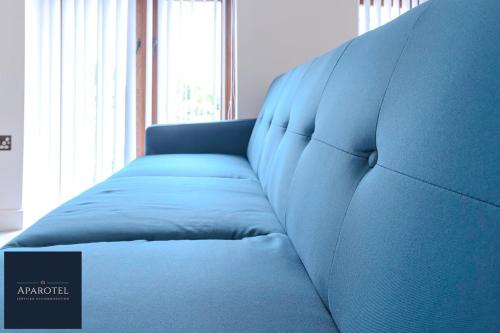 a blue couch in a room with a window at Aparotel Serviced Apartments - Stonehenge, Amesbury Town Centre in Amesbury