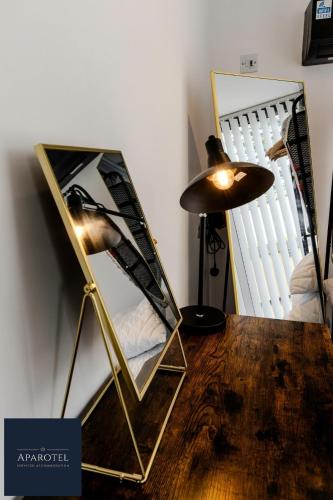 a mirror sitting on a table next to a lamp at Aparotel Serviced Apartments - Stonehenge, Amesbury Town Centre in Amesbury