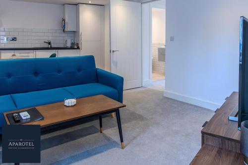 a living room with a blue couch and a coffee table at Aparotel Serviced Apartments - Stonehenge, Amesbury Town Centre in Amesbury