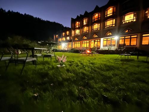 a building with benches in the grass at night at Sagar Heritage Resort, Near Mall Road Manali in Manāli