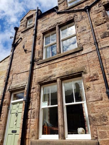 a brick building with three windows and a door at Woolly Hill House - Beautiful Townhouse in the Heart of Wooler in Wooler