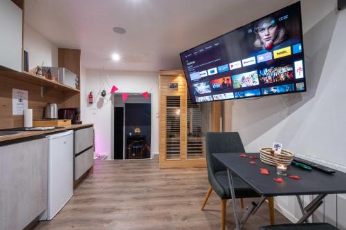 Il comprend une cuisine avec une table et une télévision murale. dans l'établissement Suite pour les Amoureux_Val d'Europe Disney, à Coupvray