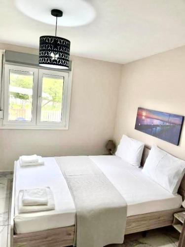a bedroom with a large white bed with two windows at Studio Coral by the sea in Neoi Epivates