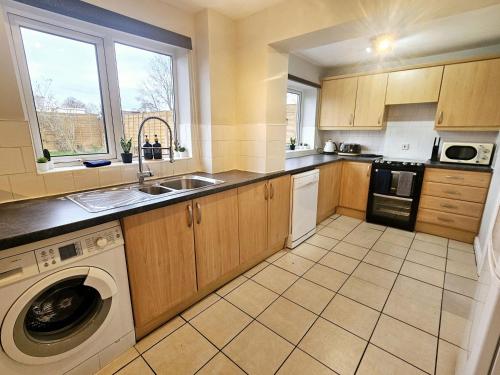 a kitchen with a washer and a sink and a dishwasher at Platt House in Wigan