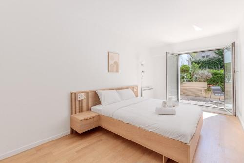 une chambre blanche avec un lit et une grande fenêtre dans l'établissement Beautiful 4P Apartment with Garden - Paris 16th, à Paris